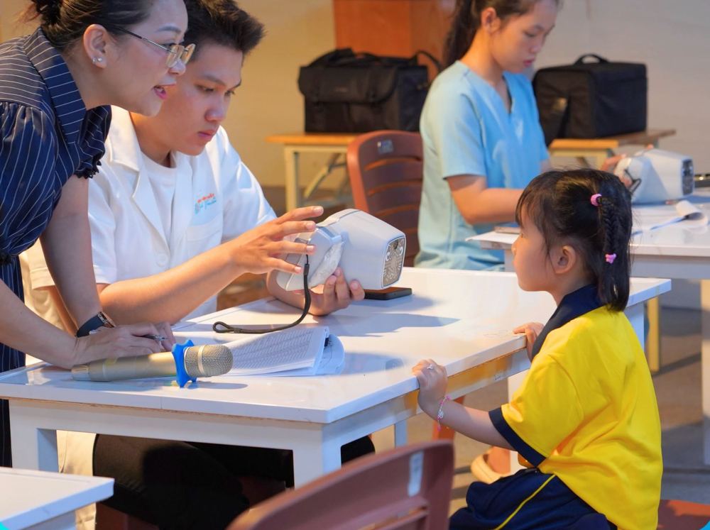 Kỹ thuật viên đo khúc xạ cho học sinh tiểu học tại trường